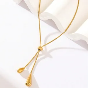 Macro detail of adjustable gold snake chain necklace with teardrop pendants on white waves