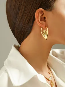 Detail van elegante gouden oorbellen met bladvormig filigraan en ovale witte steen