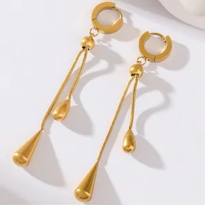 Detail view of gold tassel earrings with adjustable chain and teardrop metal pendants