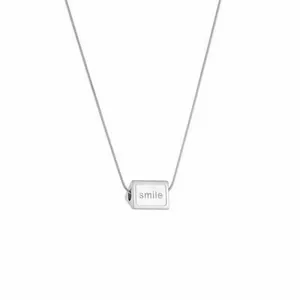 Macro shot of silver cube pendant with smile engraving on sleek stainless steel chain