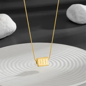 Gold titanium steel triangle smile necklace with lucky engraving on a white tray
