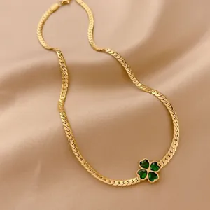 Golden titanium steel four-leaf clover necklace with green zircon on silk background