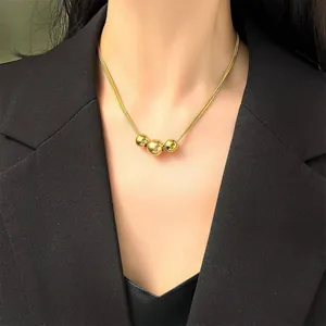 Elegant gold snake chain necklace with three polished spheres on a black suit backdrop