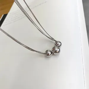 Macro shot of minimalist triple bead pendant on a layered silver tone metal chain