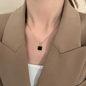 Collier chaîne dorée minimaliste avec pendentif carré noir porté par un mannequin