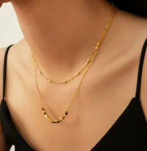 Close-up of double-layered gold beaded necklace on a model wearing a black dress