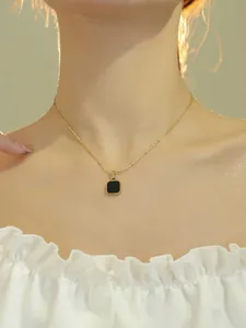 Gros plan d'un collier doré avec pendentif carré noir en émail sur un mannequin