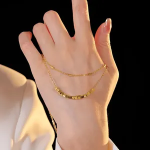 Detail view of a double-layered gold necklace with cuboid and cylindrical beads