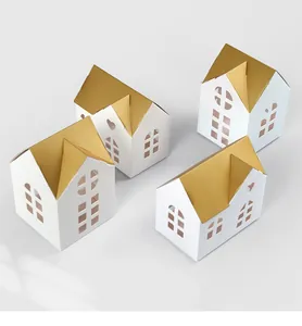 Detail of white house-shaped gift boxes with golden roofs and intricate cutout windows