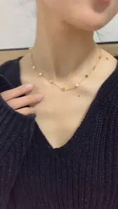 Detail view of a gold-plated titanium clover necklace on a model showing the chain length