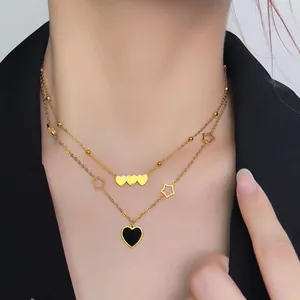 Detail of layered gold heart necklace featuring black enamel heart and star charms