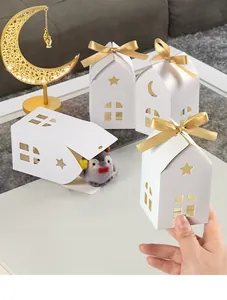 Detailed view of white house-shaped gift box with star and moon cutouts and gold bow