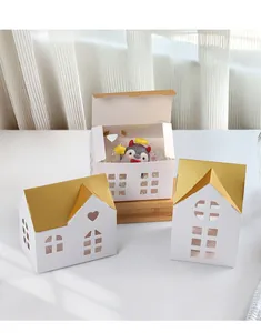 Detail of white house-shaped gift boxes with golden roofs and intricate cutout windows