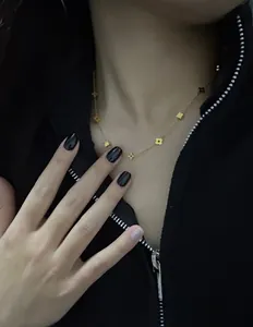 Detailed view of a gold clover and star necklace worn on a woman's collarbone