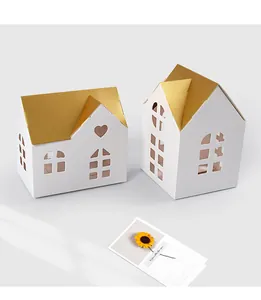 Detail of white house gift boxes with golden roofs and heart-shaped hollow patterns