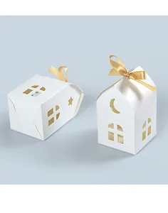 Close-up of white house-shaped gift boxes with star cutouts and golden satin ribbon bow