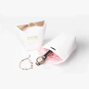 Elegant white paper gift bags with brown ribbon bows and gold merci beaucoup text