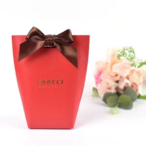 Sacchetto regalo rosso a trapezio con scritta merci dorata e fiocco in raso marrone