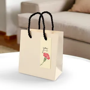 Beige gift bag with black cord handles and carnation floral tag saying you are magic