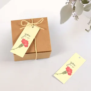 Detail of carnation gift tag with you are magic text tied to kraft paper box