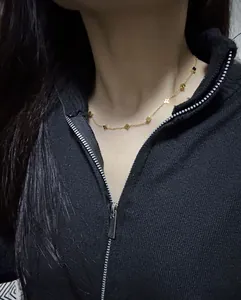 Detail of clover and star pendants on gold titanium steel necklace worn on neck