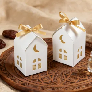 White house-shaped gift boxes with crescent moon cutouts and gold ribbons on a tray