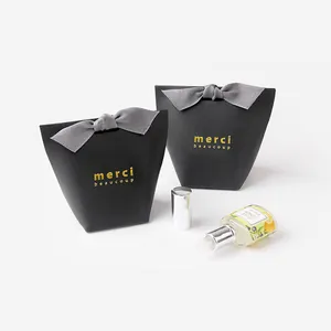 Elegant black gift bag with gold merci beaucoup text and a grey ribbon bow for festivals