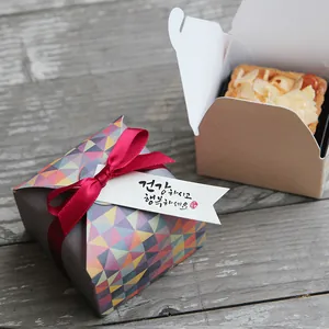 Detail of colorful geometric gift box with red ribbon and kraft paper bakery box