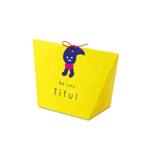 Macro shot of yellow trapezoid gift box with Be you Tiful text and blue cartoon tag