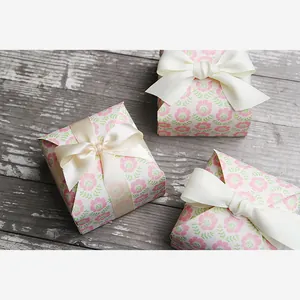 Detail of floral patterned square paper gift boxes with elegant cream satin ribbon bows