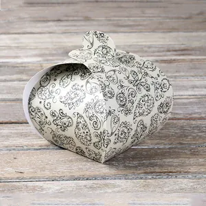 Detail of cream gift box with black paisley patterns and circular clasp on wood surface