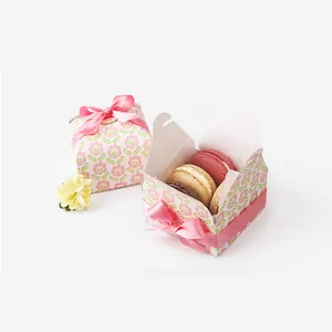 Detail view of square floral gift box with pink silk ribbon and colorful macarons inside