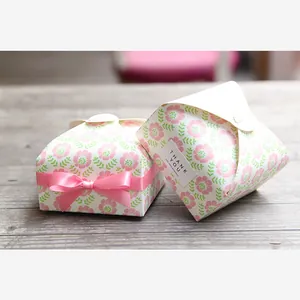 Detail of vintage floral gift box with pink ribbon and Thank You seal on wood surface