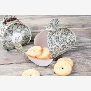 Detail of paisley wedding favor box with thank you sticker and cookies on wood