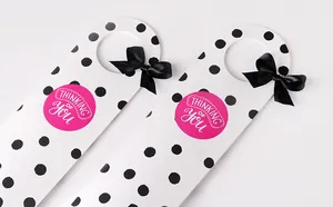 Gros plan d'une boîte cadeau blanche à pois noirs avec autocollant rose et nœud