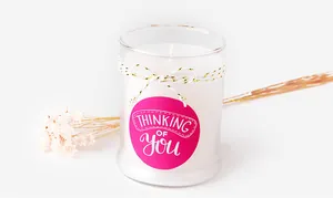 Gros plan sur l'étiquette rose Thinking of You d'une bougie parfumée en verre