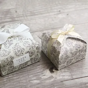 Close-up of square paisley gift boxes with ribbon bows on light wood background