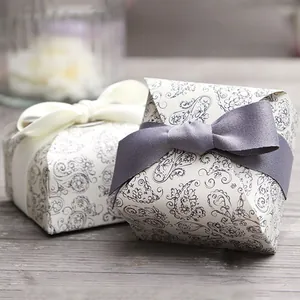 Elegant paisley pattern gift boxes with silk ribbon bows on a rustic wooden background