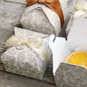 Detail of paisley print gift boxes with satin ribbons and small pastries inside