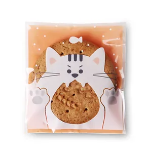 Detalle de bolsa de galletas naranja con gato, lunares blancos y empaque translúcido