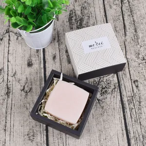Detail of pink handmade soap in black gift box with merci labels and raffia filling