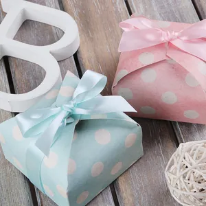 Scatole regalo a pois blu e rosa con nastri di raso coordinati su superficie in legno