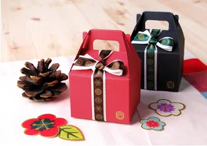 Détail de boîtes cadeaux rouges et noires avec motifs dorés et nœuds en ruban