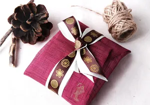 Détail du sac cadeau rouge avec ruban doré et décorations naturelles rustiques