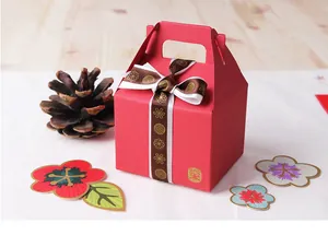 Details einer roten Geschenkbox mit goldgemustertem Schleifenband und Pflaumenblüten-Deko