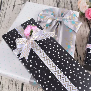 Papier cadeau à pois avec ruban satiné de luxe et décor floral sur bois clair