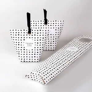 Detailed view of polka dot paper gift boxes with black silk handles and thank you labels