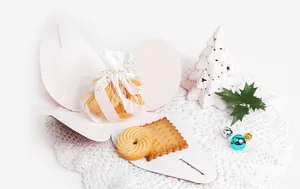 Dettaglio di una scatola regalo a farfalla rosa con biscotti e decorazioni natalizie