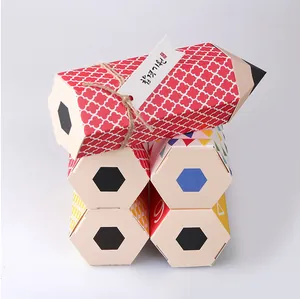 Macro shot of pencil-shaped candy gift boxes with colorful geometric patterns and jute tags