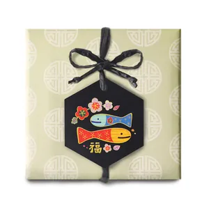 Green gift box with black rope bow and hexagonal Fu character tag featuring plum blossoms